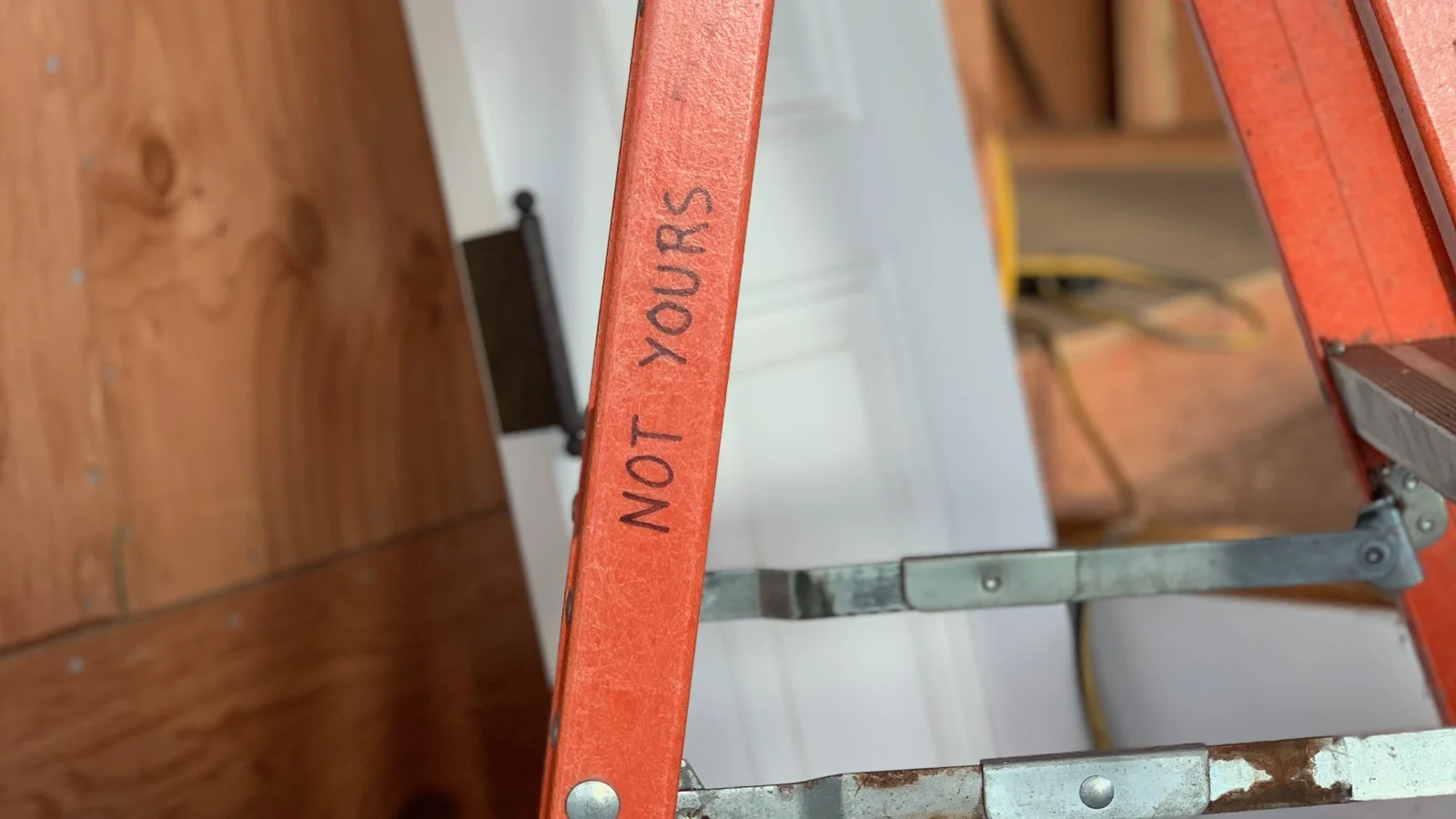 Handwritten sign on a ladder reading 'NOT YOURS'